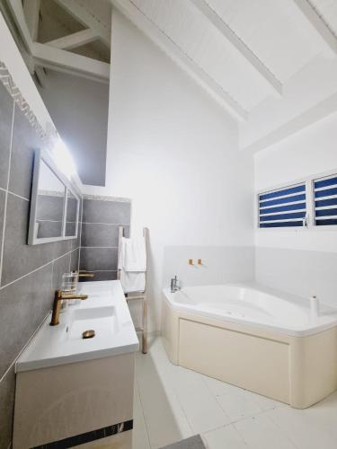 a white bathroom with a tub and a sink at Sandy Bay Villa Opale in Le Moule