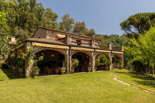 a large house with a porch in the grass at Finca La Lobera in Candeleda