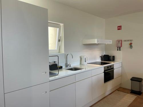 a white kitchen with white cabinets and a sink at Casa do Convento in Tavira