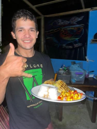 a man holding a plate of food with a piece of cake at fenix soul hostel ocean view in Drake