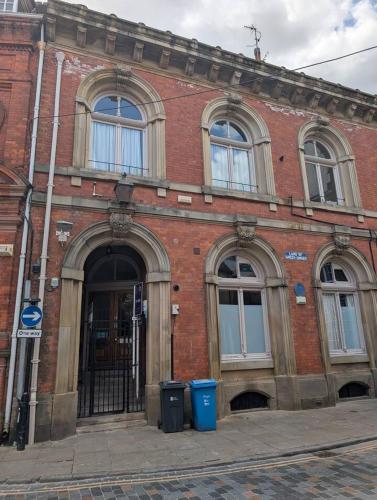 an old brick building with a door and two trash cans at Charming Old Town Apartment in Hull