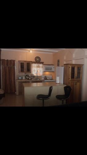 a kitchen with a counter and two black chairs at Beautiful home in Maloney Gardens, Arouca Trinidad in Arouca