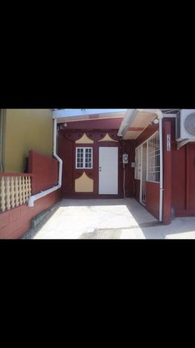 a building with a garage with two white doors at Beautiful home in Maloney Gardens, Arouca Trinidad in Arouca