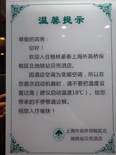 a sign with chinese writing on it at GreenTree Inn Shell Hotel Shanghai Waigaoqiao Free Trade Zone North Subway Station Branch in Shanghai