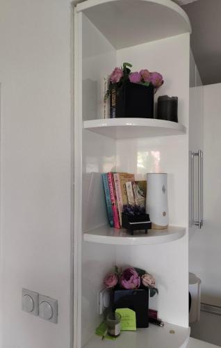 a white book shelf with books and flowers on it at Jove Apartments in Bitola
