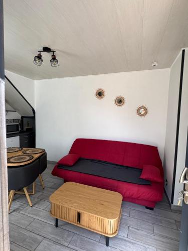 un salon avec un canapé rouge et une table dans l'établissement Chez Sylviane Rez-de-Chaussée 200 m de la mer, à Luc-sur-Mer