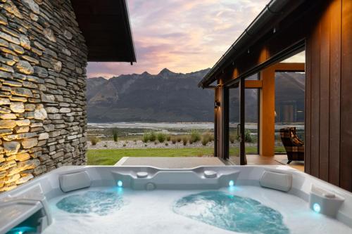 a jacuzzi tub with a view of the mountains at Whenua Lodge - Our Land Lodge in Glenorchy