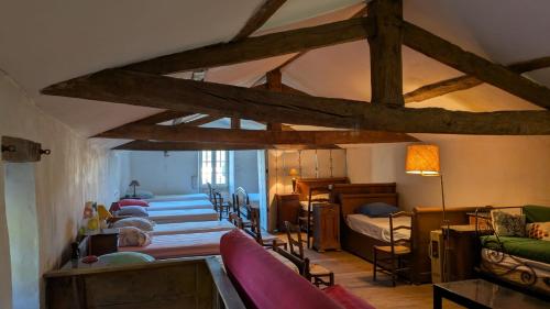 une pièce avec des rangées de lits dans une pièce avec des poutres en bois dans l'établissement Le Prieuré Saint Pierre, gîtes et chambres d'hôtes dans un parc classé, à Réaumur
