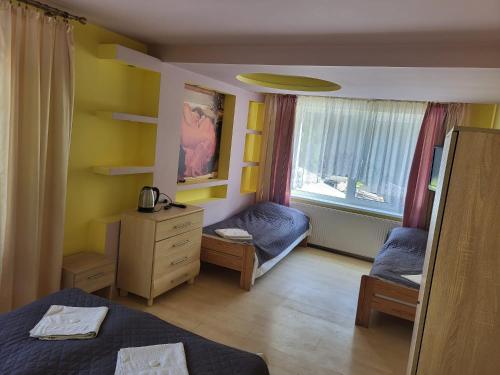 a bedroom with two beds and a dresser and a window at Pokoje Goscinne Korsarz - przy trasie rowerowej R10 in Ustka