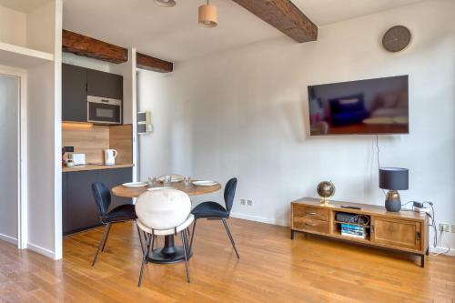 - un salon avec une table, des chaises et une télévision dans l'établissement Petit Castel - charmant T2 de 39m au cœur de Rouen Rue du Gros-Horloge !, à Rouen