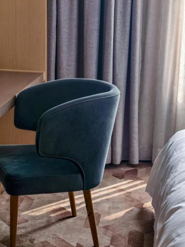 a blue chair sitting next to a bed in a room at 佛山顺德青森酒店-长鹿旅游休博园店 in Shunde