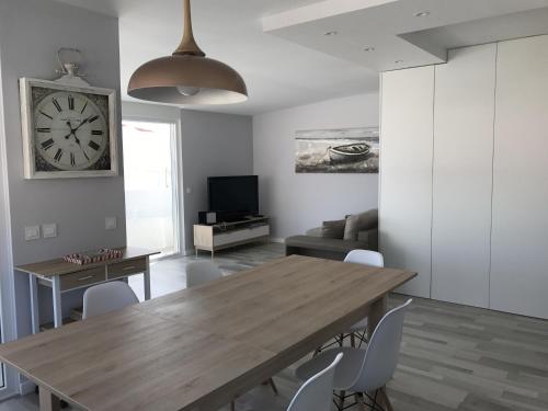 a dining room with a table and a clock on the wall at Blue Bay Beach Apartment in Sesimbra