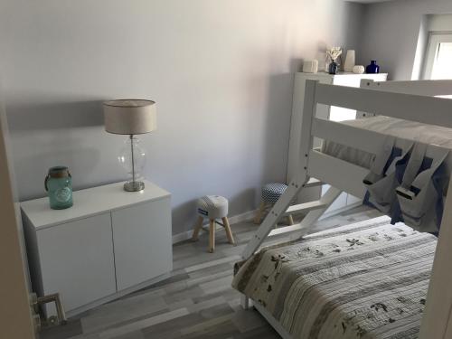 a white bedroom with a bunk bed and a lamp at Blue Bay Beach Apartment in Sesimbra