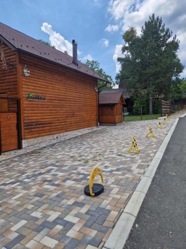 a brick parking lot with a building and yellow barriers at Vila Fruškica in Vrdnik