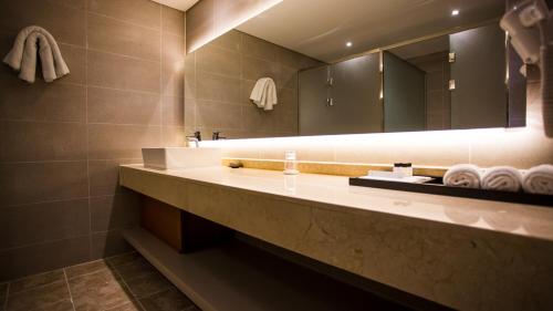 a bathroom with a sink and a mirror and towels at J Square Hotel and Wedding in Jinju