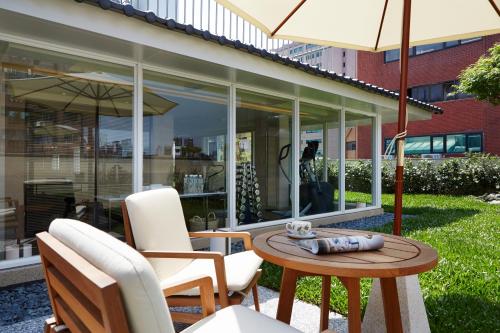 a patio with chairs and a table with an umbrella at Taipei Fullerton Hotel-Maison North in Taipei