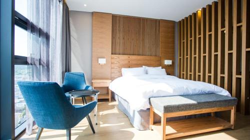 sypialnia z łóżkiem i 2 niebieskimi krzesłami w obiekcie J Square Hotel and Wedding w mieście Jinju