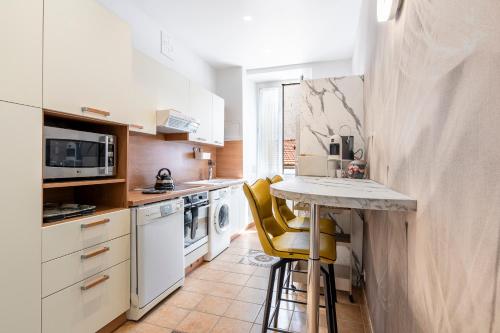 une cuisine avec un comptoir et des tabourets de bar jaunes dans l'établissement Appartement 2 chambres proche plage climatisé, à Nice