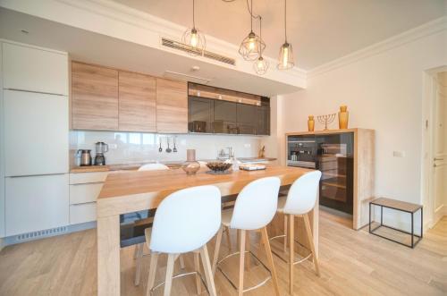 a kitchen with a wooden table and white chairs at Lustica Bay Marina Village by 2BHome in Lustica