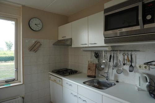 a kitchen with a sink and a clock on the wall at Kustverhuur, Park Schoneveld Stern 188 in Breskens