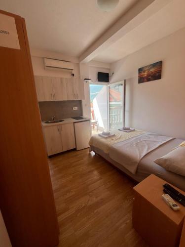 um pequeno quarto com uma cama e uma cozinha em Vasiljević apartmani em Igalo