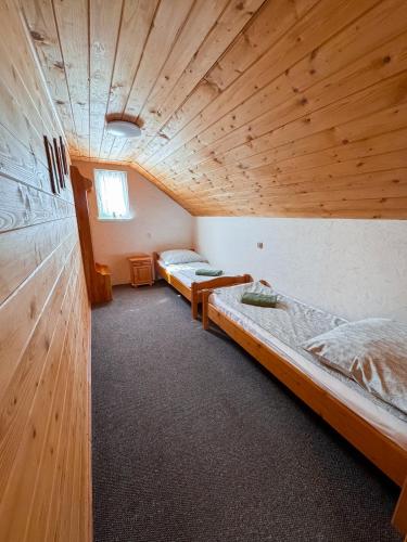 two beds in a room with a wooden ceiling at Domek na wzgórzu in Tabaszowa