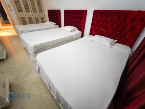 three beds in a room with red headboards at Marina Yasmine Hammamet Luxury residence in Yasmine