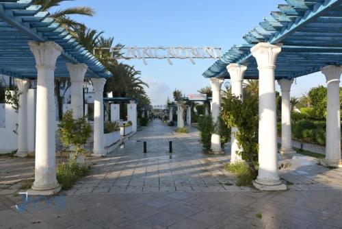 an empty arcade with white columns and a blue roof at Marina Yasmine Hammamet Luxury residence in Yasmine