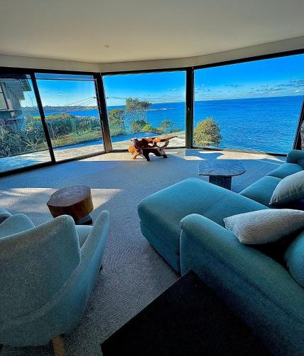 a living room with blue couches and a view of the ocean at Ocean view home South Coogee in Sydney