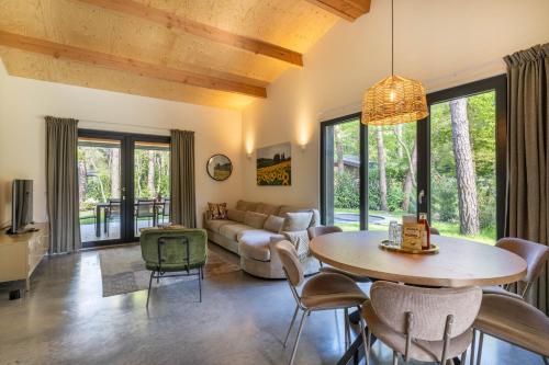 a living room with a table and a couch at Luxe familiehuis in parkbos in Giethmen