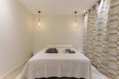 a white bedroom with a bed with two pillows on it at Les Villas De Mandelieu by Halldis in Mandelieu-la-Napoule