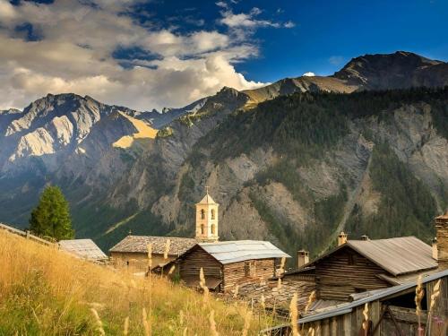 an old building with a church in front of a mountain at CASA-Lodge L’Inverno pour 2 personnes in Molines-en-Queyras