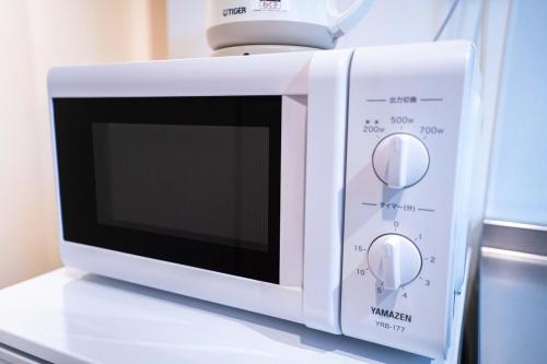 a white microwave oven sitting on top of a counter at 5 min walk from Gotanno station 20sqm apartment with private toilet and bathroom Direct access to popular travel destinations such as Ueno in Tokyo
