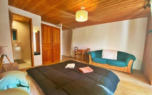 a bedroom with a blue bed and a couch at CASA-Lodge L’Inverno pour 2 personnes in Molines-en-Queyras