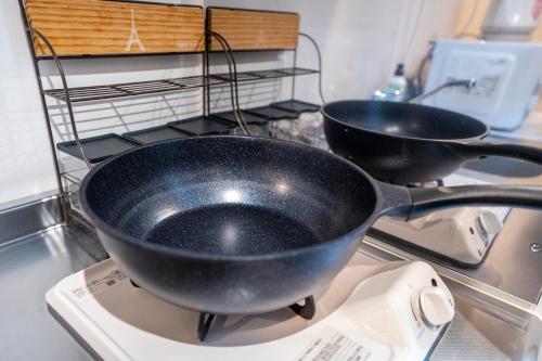 two frying pans sitting on top of a stove at 5 min walk from Gotanno station 20sqm apartment with private toilet and bathroom Direct access to popular travel destinations such as Ueno in Tokyo