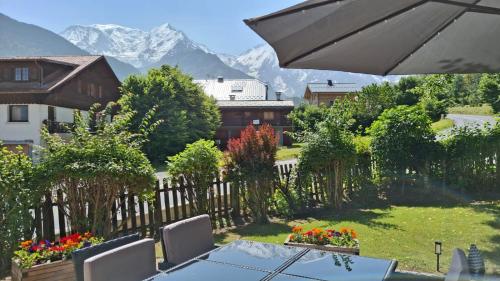 une table et des chaises dans un jardin avec des montagnes en arrière-plan dans l'établissement Chalet OurSourie, à Saint-Gervais-les-Bains