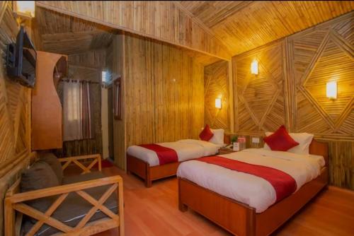 two beds in a room with wooden walls at Babylon Bamboo Cottage in Pokhara