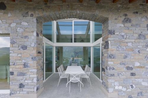 a stone walled patio with a white table and chairs at Villa Miraggio by MyVillaCollection in Tremezzo