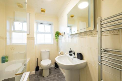 a bathroom with a sink and a toilet and a mirror at SionStays - Honeysuckle Court - Close to City Centre! in Peterborough