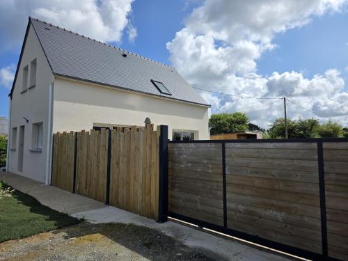 a white house with a wooden fence at Jolie maison neuve proche plages GR34 et port de Aber Wrach in Landéda