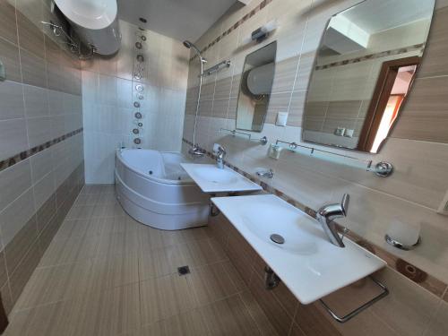 a bathroom with two sinks and a tub and a mirror at Dani beach Sozopol in Sozopol