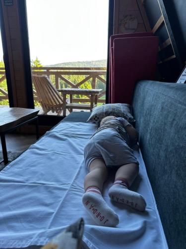 a child laying on a couch with his head on a bed at Hanina Village Resort - l i ll in Čajniče