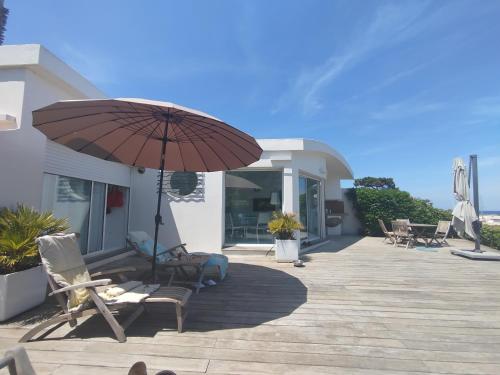 une terrasse avec des chaises et un parasol dans une maison dans l'établissement Sur la plage, à Lumio
