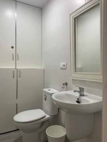 a white bathroom with a toilet and a sink at Córdoba 8 by 7Escalones in Rota