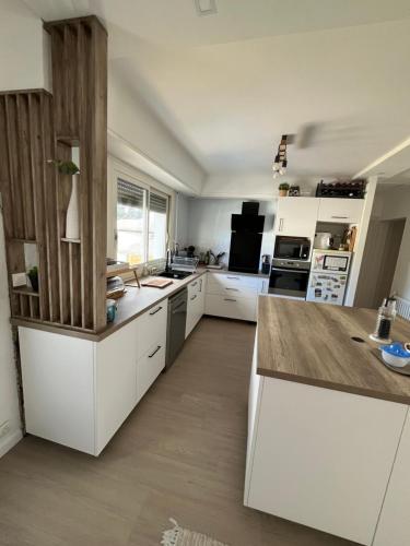 une cuisine avec des armoires blanches et un comptoir en bois dans l'établissement La Bergeronnette, à Ondres