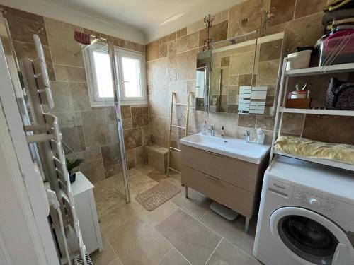une salle de bain avec douche et lavabo et une machine à laver dans l'établissement La Bergeronnette, à Ondres