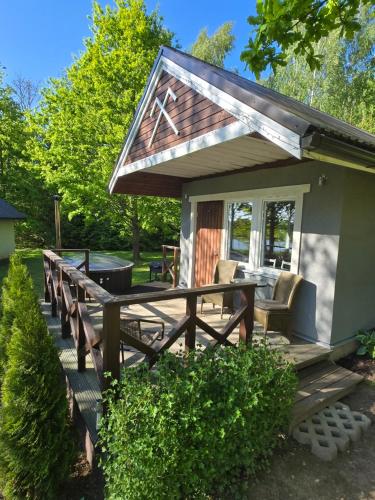 a small cabin with a deck with a table and chairs at Līdumnieki in Vērgale