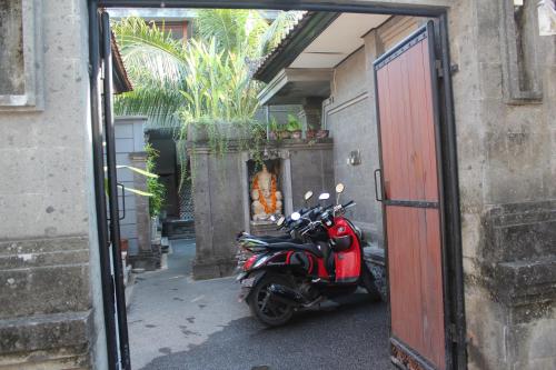 a red scooter parked in front of a building at Letos Kubu Homestay in Kuta