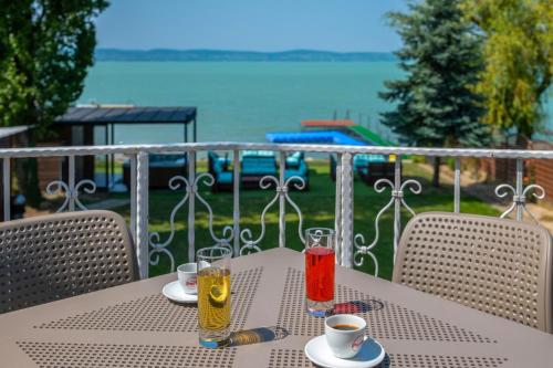 a table with two glasses of juice on a balcony at Villa My Lake in Zamárdi
