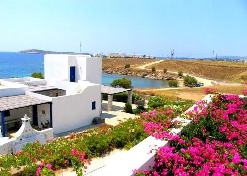 a white building with pink flowers in front of the ocean at Villa Maria, Golden Beach, Paros in Kampos Paros